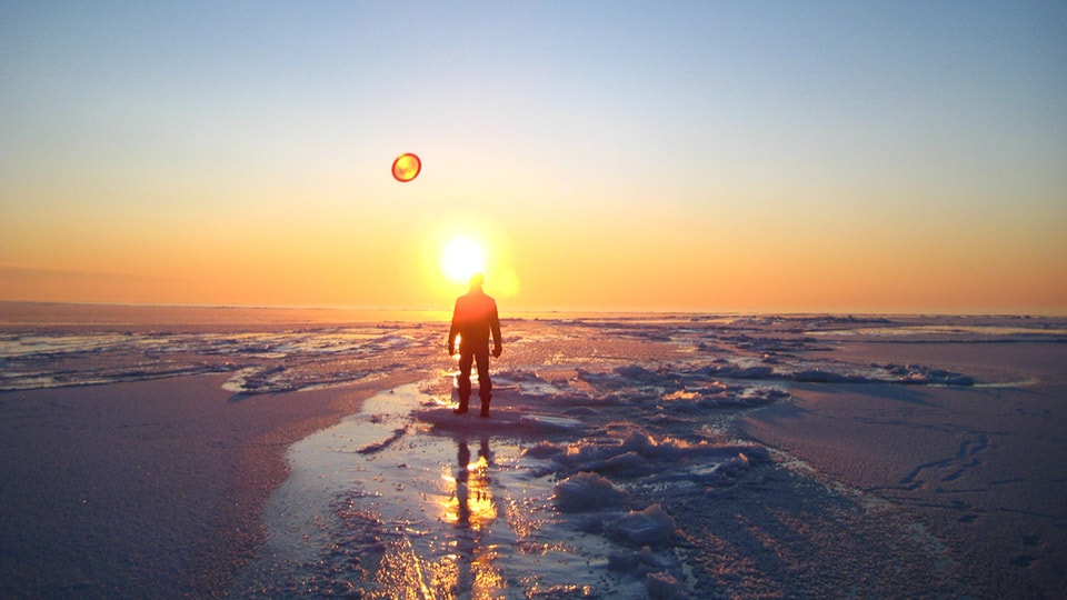 With the sun setting over the Baltic Sea Coast in Estonia, a figure stands on the frozen lake looking to the horizon.